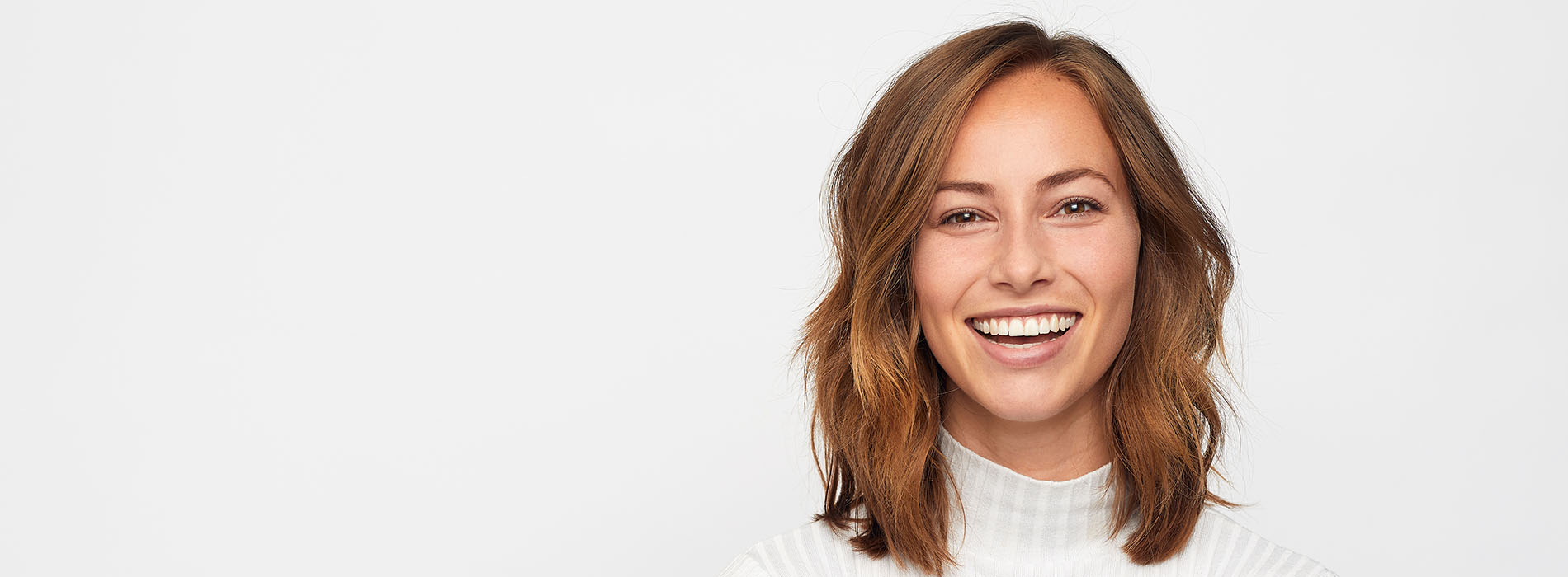 The image features a smiling woman with short hair, wearing a white top, standing against a plain background.