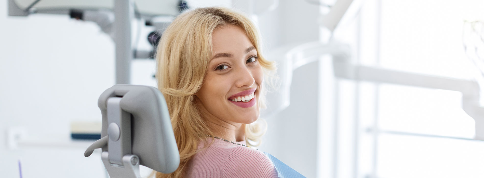 Woman in dental chair, smiling at camera.