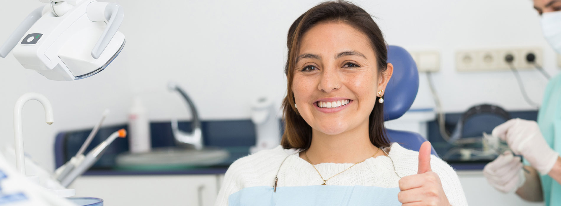 A woman in a dental office, smiling at the camera while seated in a dentist s chair.