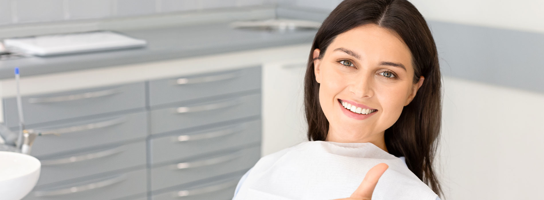 The image shows a woman with a smile, standing in front of a dental clinic setting.