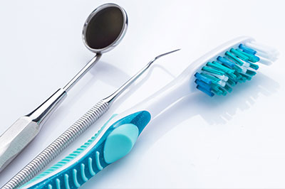 The image features a collection of dental tools, including a toothbrush with blue bristles, a pair of scissors, and other instruments typically found in a dentist s office.