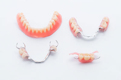 The image displays a collection of dental implants, including crowns and bridges, showcasing the artificial teeth used in dentistry.