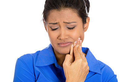 A woman with a concerned expression, holding her finger to her mouth, possibly indicating pain or discomfort.