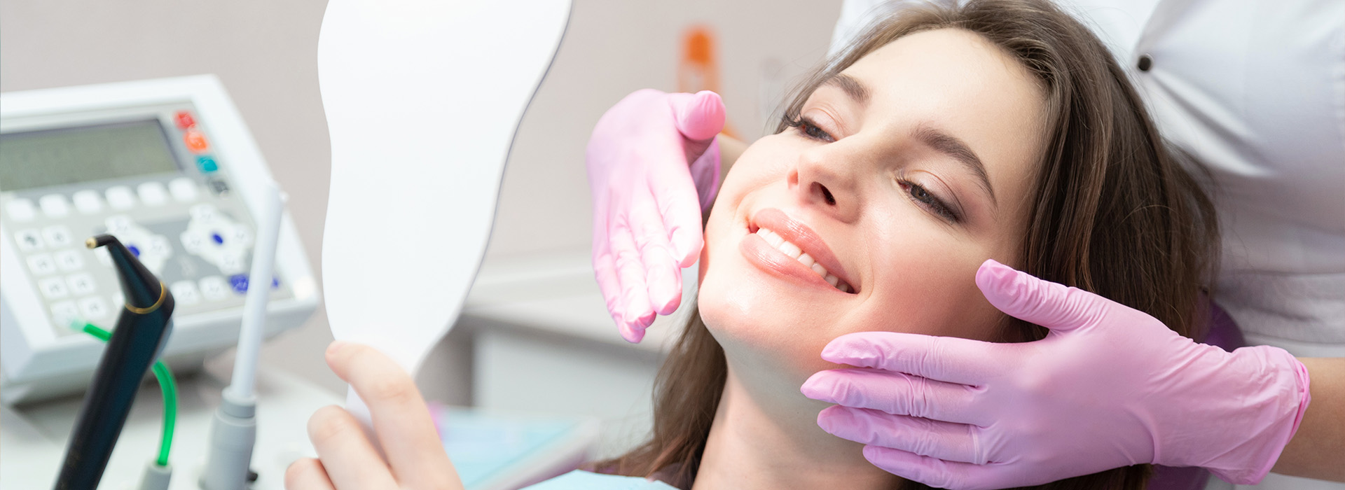 A woman receiving a dental treatment with a dentist using a drill.