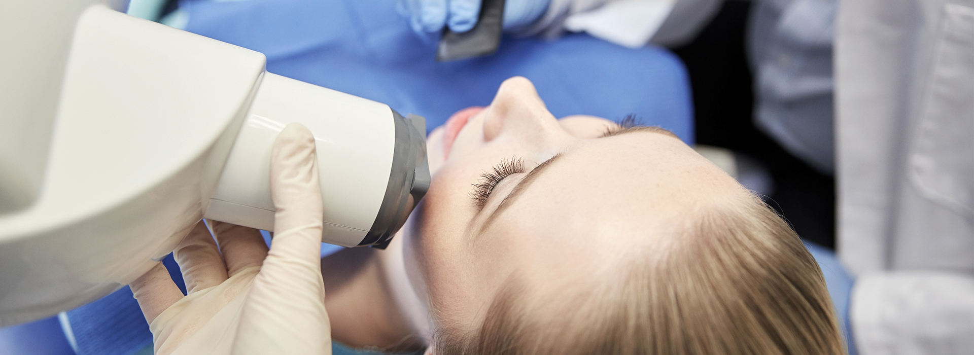 A woman receiving a dental implant procedure with a dentist using a microscope to guide the placement.