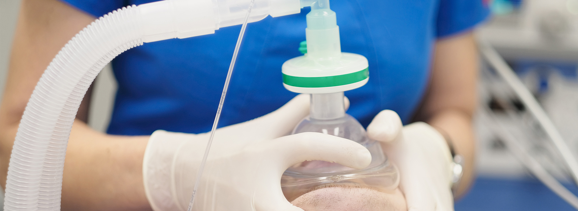 The image shows a person wearing gloves and a blue shirt, holding a clear plastic bag with a green cap containing a white substance, presumably in a laboratory or medical setting.