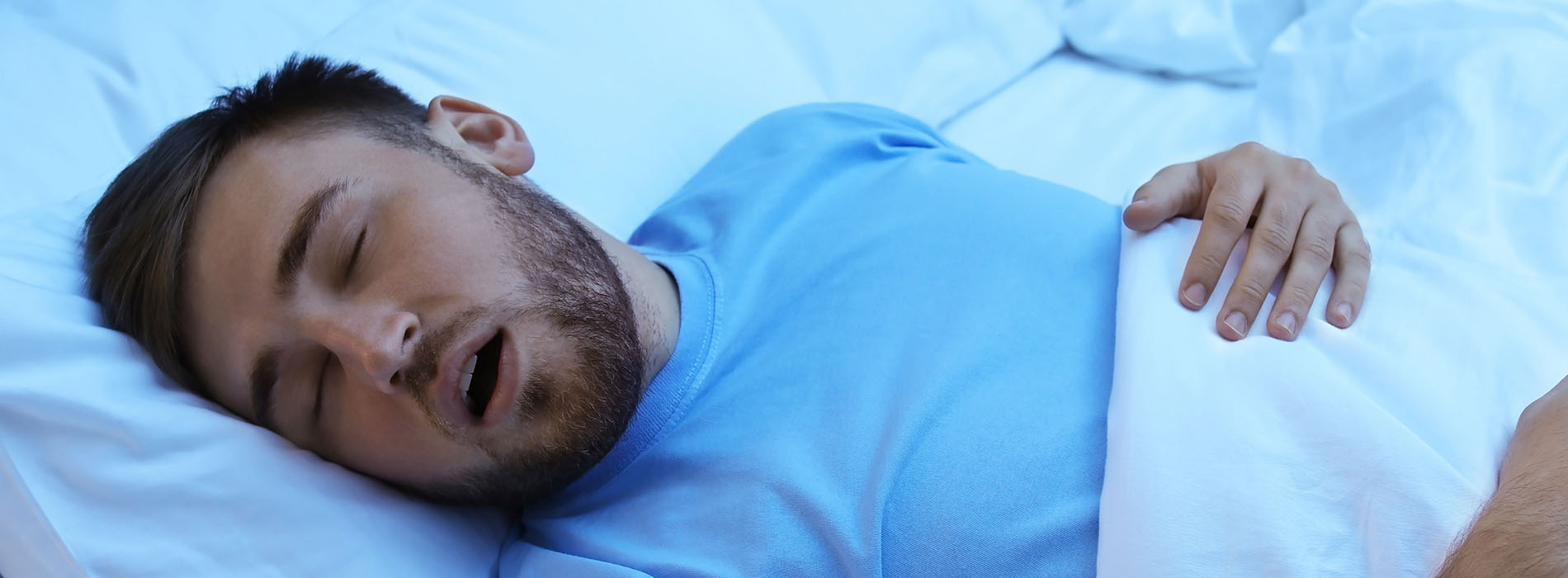 A man is lying in bed with a pillow, appearing to be asleep or resting.