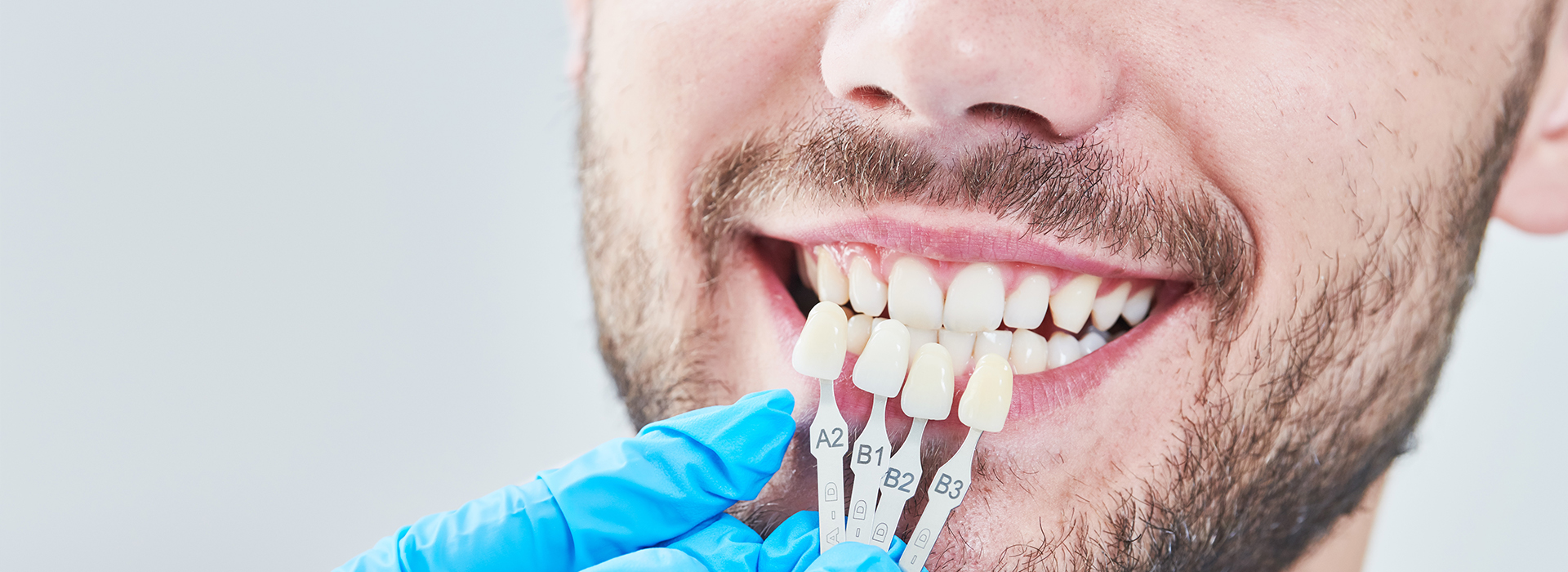 The image shows a person smiling, with their teeth being worked on by dental tools visible in the foreground.