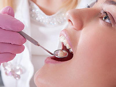 A dental professional performing a teeth cleaning procedure on a patient, with the patient wearing protective eyewear.