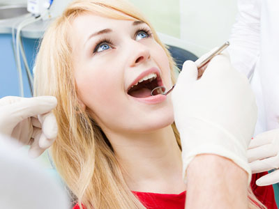 Woman in a dental chair receiving treatment, with dental tools visible.